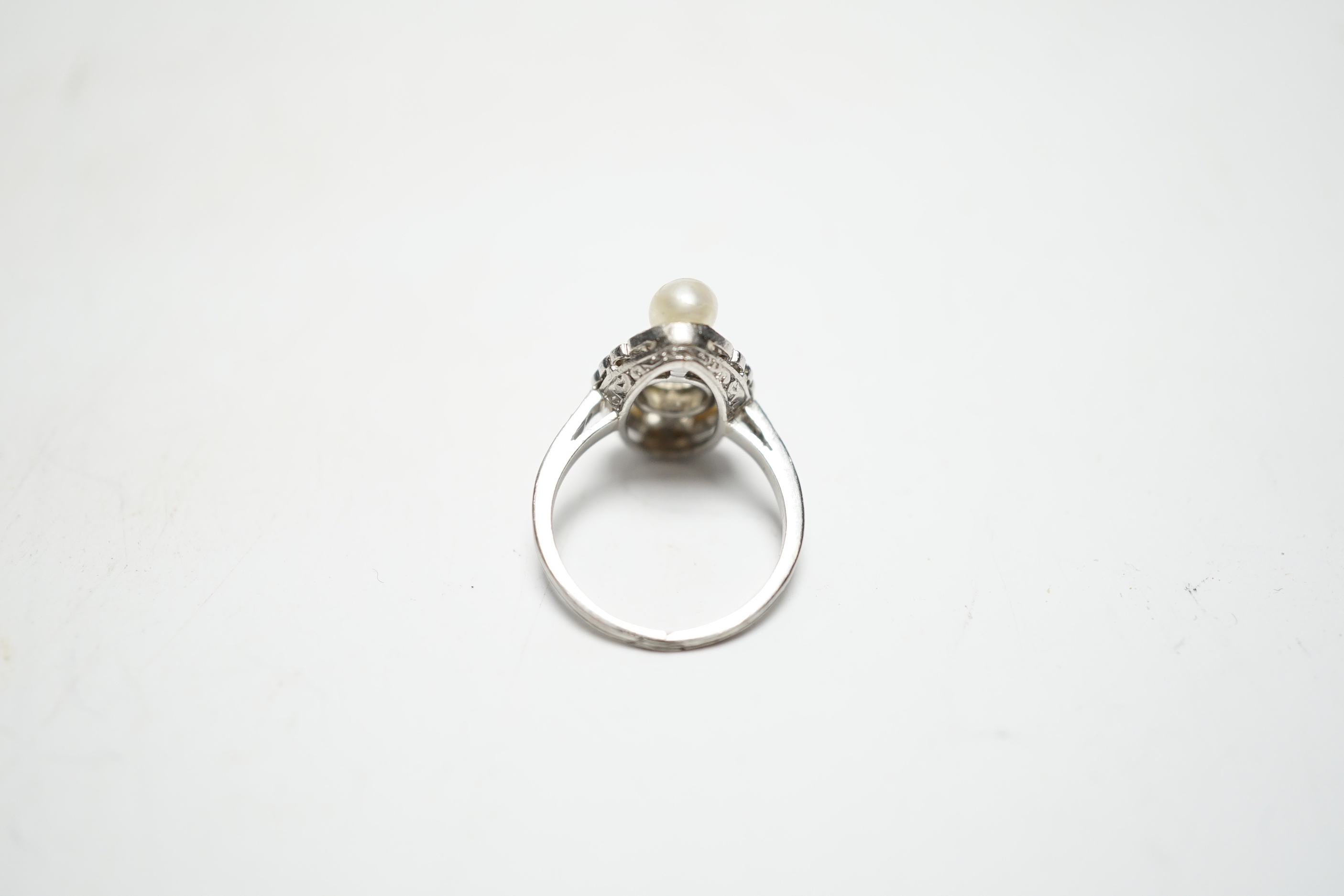 A white metal single stone diamond and two stone cultured pearl set oval ring, with diamond chip set borders and shoulders, size F, gross weight 4.4 grams.